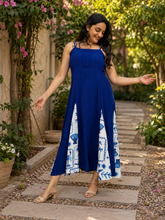 Woman in royal blue seashell print panelled maxi dress walking along a garden pathway
