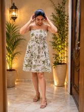 Woman in olive print strapless tiered mini dress walking indoors