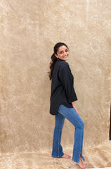 Side view of black relaxed-fit shirt with rolled cuffs and flared denim
