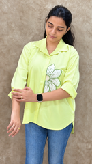 Close-up of the bead and thread handwork on the lime green shirt's apple blossom motif