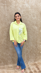 Front view of lime green flower motif handwork shirt with buttoned cuffs and flared denim
