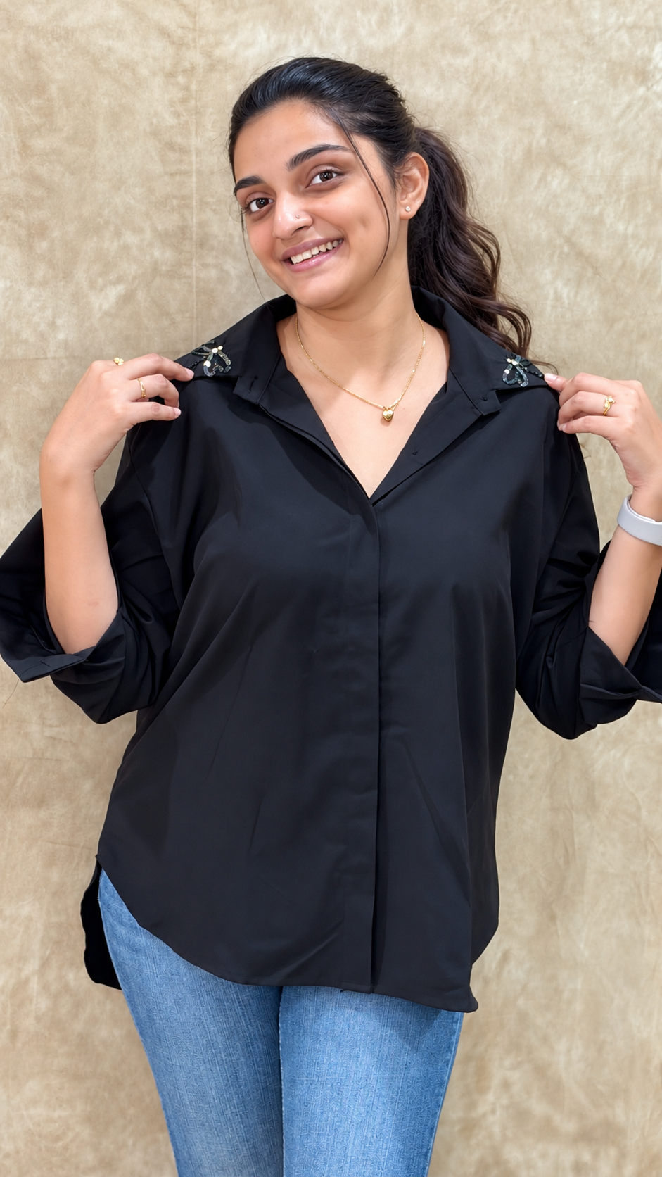 Woman in black shirt with beaded dragonfly handwork on both collar tips, worn with blue jeans