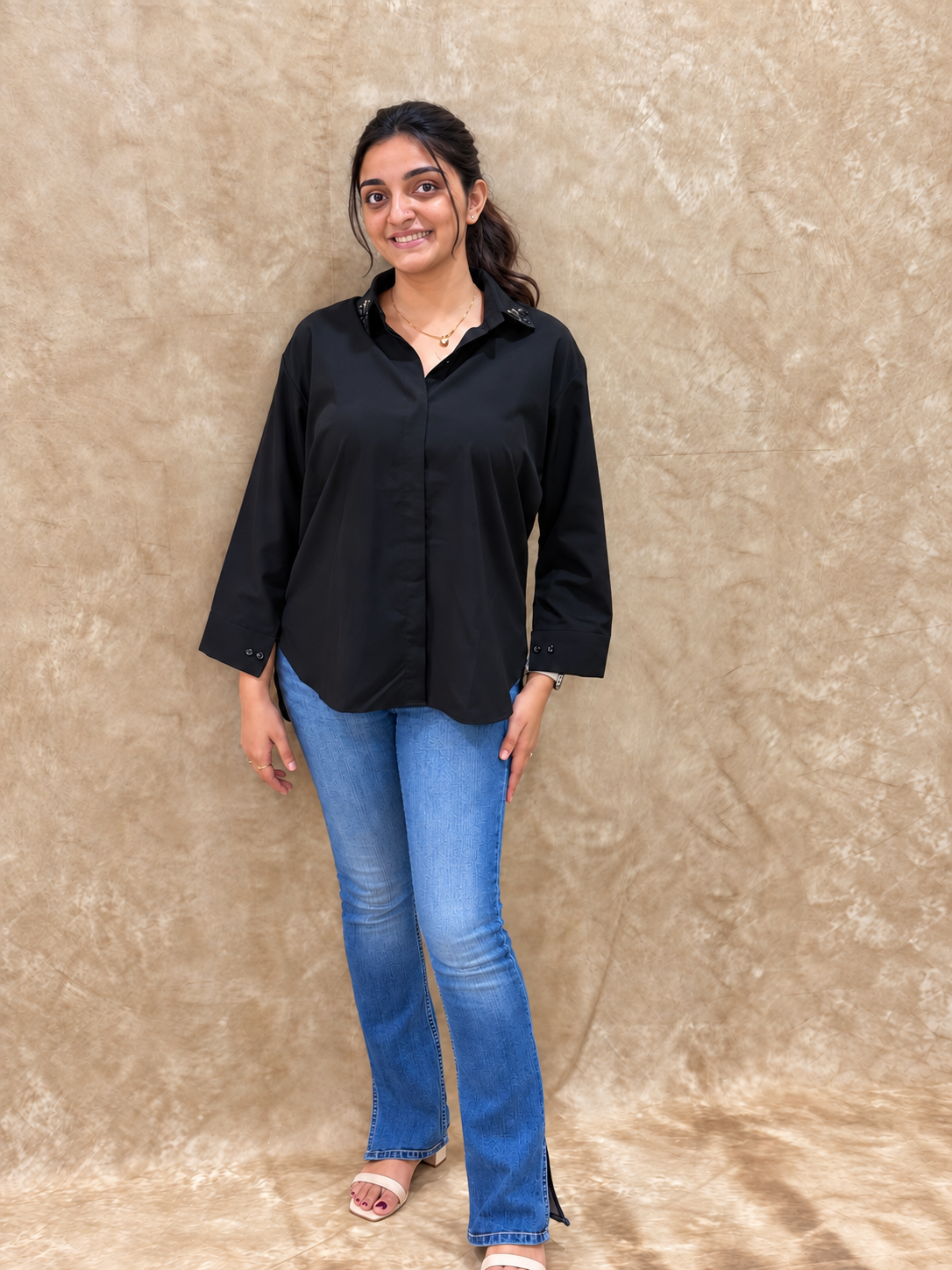 Full-length view of black dragonfly handwork shirt with flared jeans and nude heels