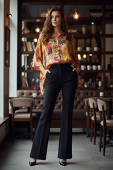 Model wearing floral tunic with flared black pants at café